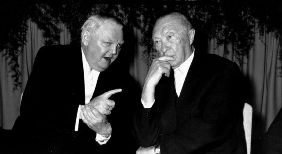Ludwig Erhard und Konrad Adenauer sitzen zusammen an einem Tisch und unterhalten sich
