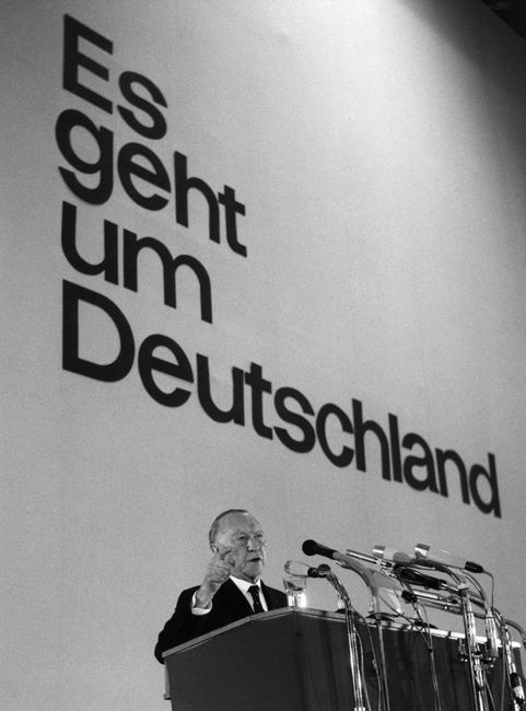 Schwarz-Weiss-Aufnahme von Konrad Adenauer in einer Ansprache vor dem großen Schriftzug "Es geht um Deutschland"