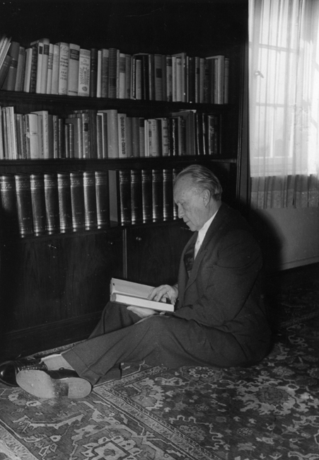 Schwarz-Weiss-Aufnahme von Konrad Adenauer beim Lesen vor einem Bücherschrank