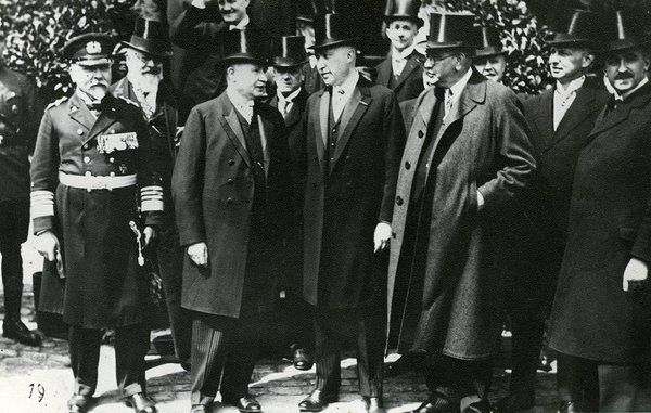 Schwarz-Weiss-Aufnahme von Konrad Adenauer mit einer Gruppe Herren in Anzügen und Zylindern