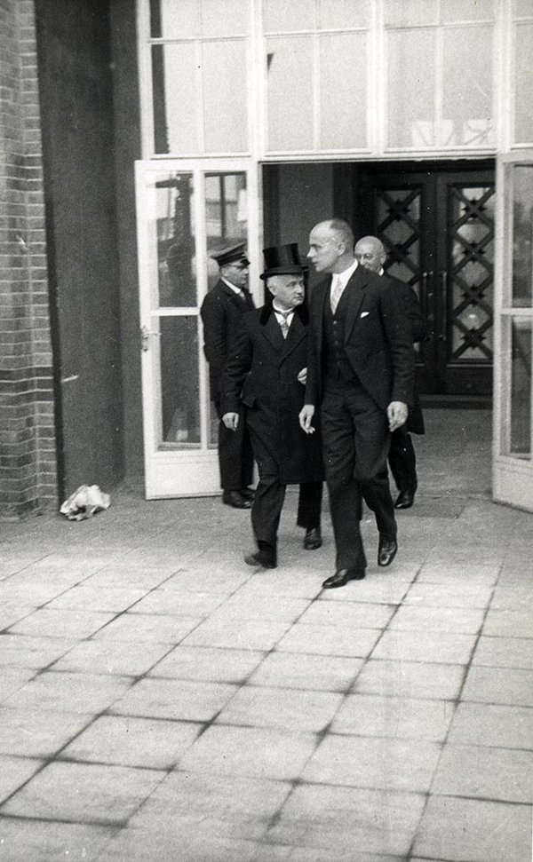 Schwarz-Weiss-Aufnahme von Konrad Adenauer mit zwei Männern beim Verlassen eines Gebäudes