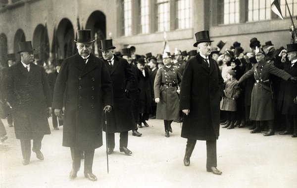 Schwarz-Weiss-Aufnahme von Paul von Hindenburg und Konrad Adenauer auf einer von Zuschauern umgebenen Straße