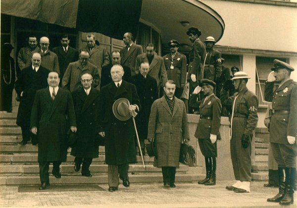 Schwarz-Weiss-Aufnahme von Konrad Adenauer mit anderen Männern auf den Stufen vor einem Gebäude