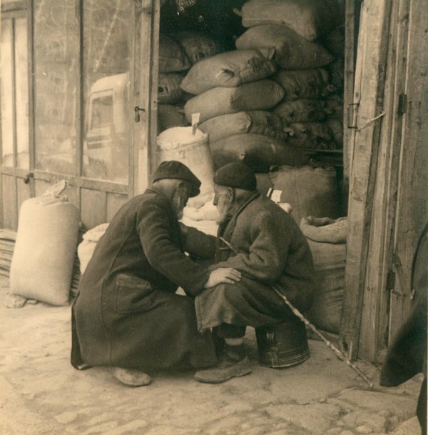 Schwarz-Weiss-Aufnahme von zwei Männern auf der Straße vor einem Lagerraum