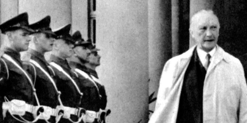 Konrad Adenauer schreitet durch Soldaten, die links und rechts Spalier stehen.