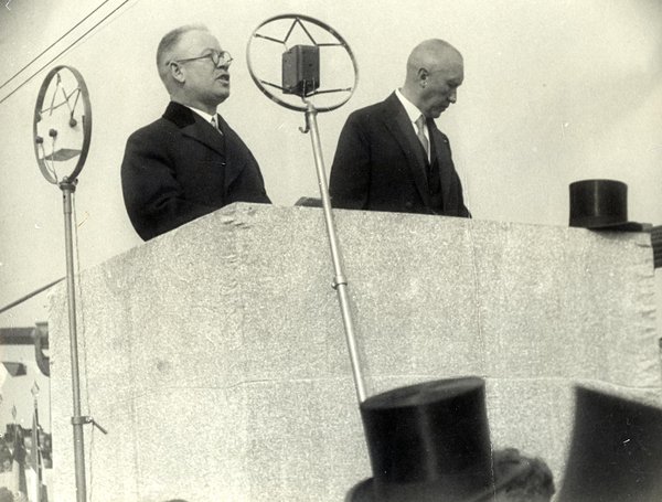 Schwarz-Weiss-Aufnahme von Konrad Adenauer und einem anderen Mann hinter zwei Mikrofonen