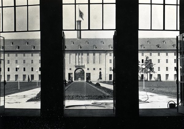 Schwarz-Weiss-Aufnahme von einem Gebäude, das durch die gegenüberliegende Fensterfront fotografiert wurde