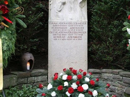 Grabstein Konrad Adenauers mit rot-weißen Bulmen davor
