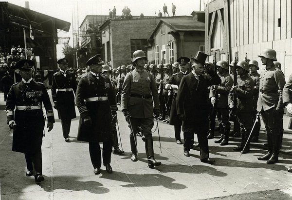Schwarz-Weiss-Aufnahme von Konrad Adenauer in Begleitung von Militär am Hafen