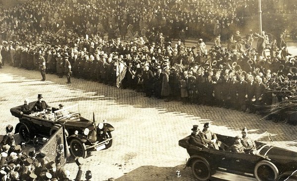 Schwarz-Weiss-Aufnahme von zwei Automobilen, umgeben von Zuschauern am Straßenrand