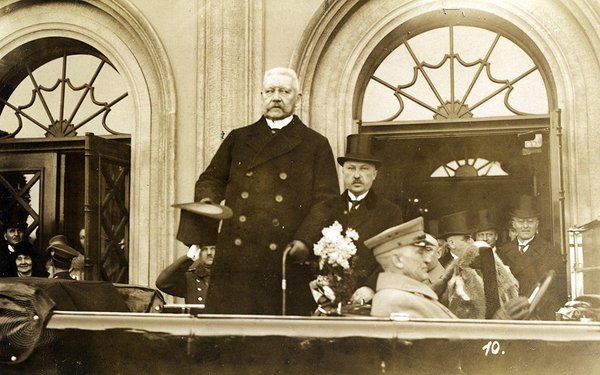 Schwarz-Weiss-Aufnahme von Paul von Hindenburg und Konrad Adenauer hinter einem Automobil