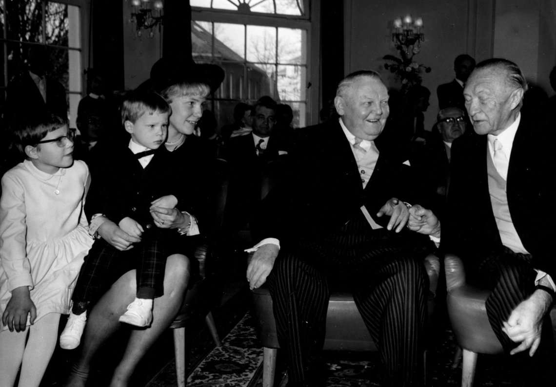 Elisabeth Werhahn mit Kind auf dem Schoß, neben ihr sitzen Ludwig Erhard und Konrad Adenauer