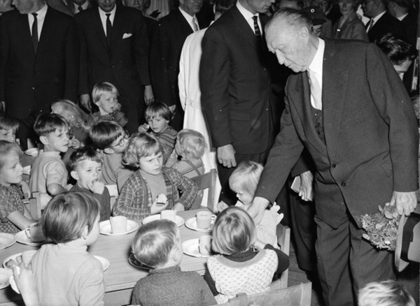Schwarz-Weiss-Aufnahme von Konrad Adenauer neben einem Tisch an dem Kinder sitzen