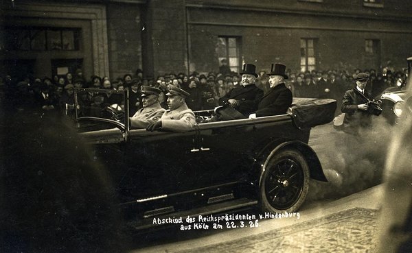 Schwarz-Weiss-Aufnahme von Paul von Hindenburg und Konrad Adenauer in einem Automobil