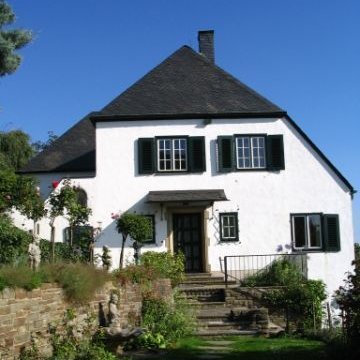 weißes Haus mit dunkel-grauem Dach und Vordergarten