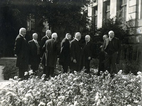 Schwarz-Weiss-Aufnahme von Konrad Adenauer in einer Gruppe vor Rosensträuchern