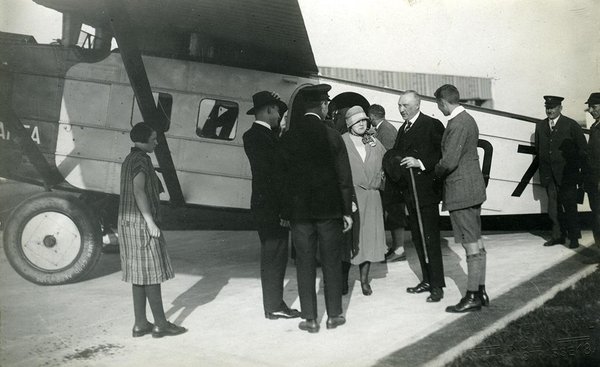 Schwarz-Weiss-Aufnahme von Konrad Adenauer mit anderen Personen vor einem Flugzeug