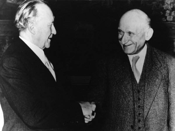 Schwarz-Weiss-Aufnahme von Konrad Adenauer und Robert Schuman beim Händeschütteln