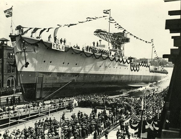 Schwarz-Weiss-Aufnahme von Menschenmassen neben einem großen Schiff im Hafen