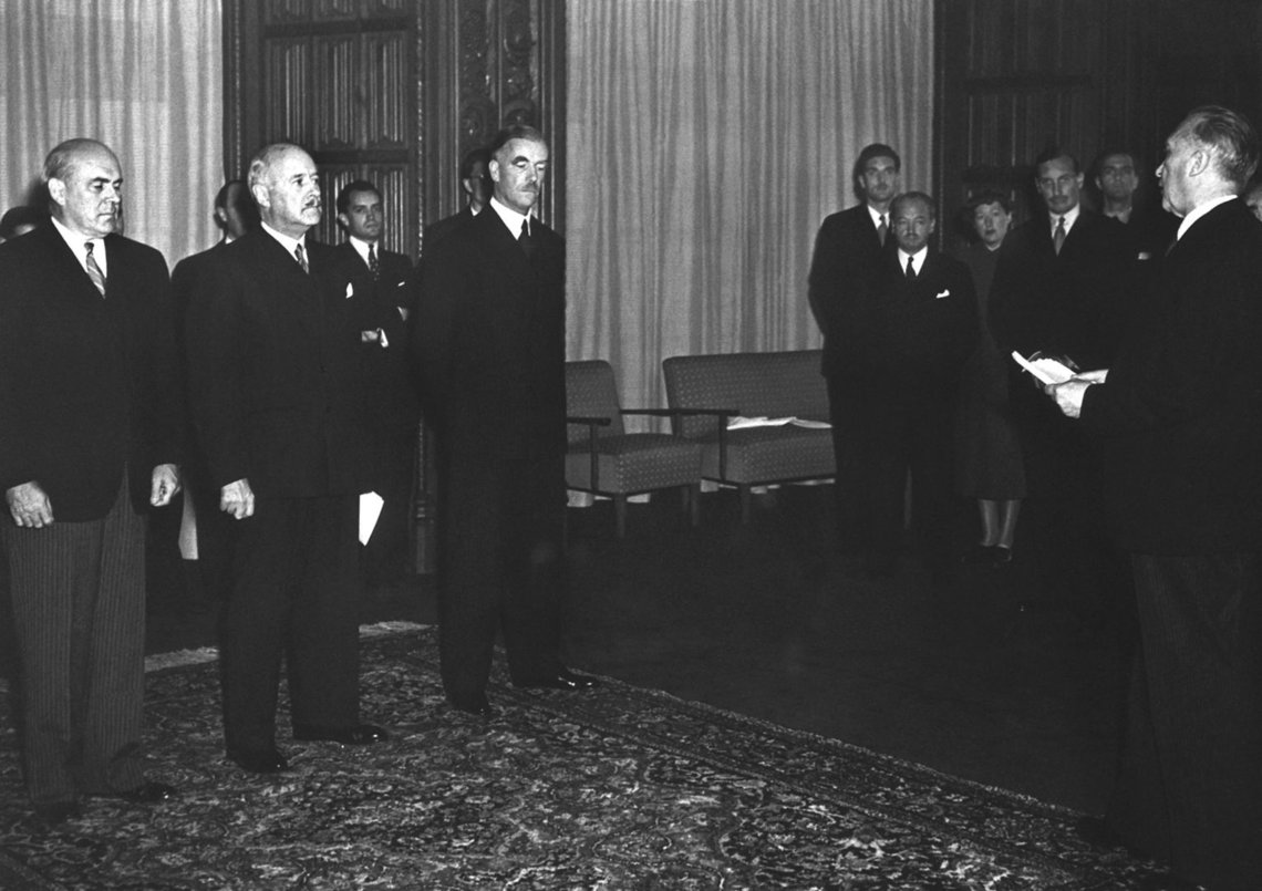 Konrad Adenauer hat einen Zettel in der Hand und vor ihm stehen die 3 Hohen Komissare