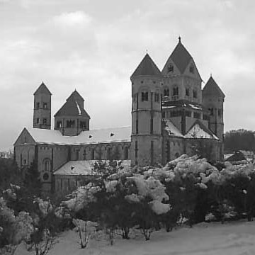 Die Abtei Maria Laach im Winter, davor verschneite Büsche 