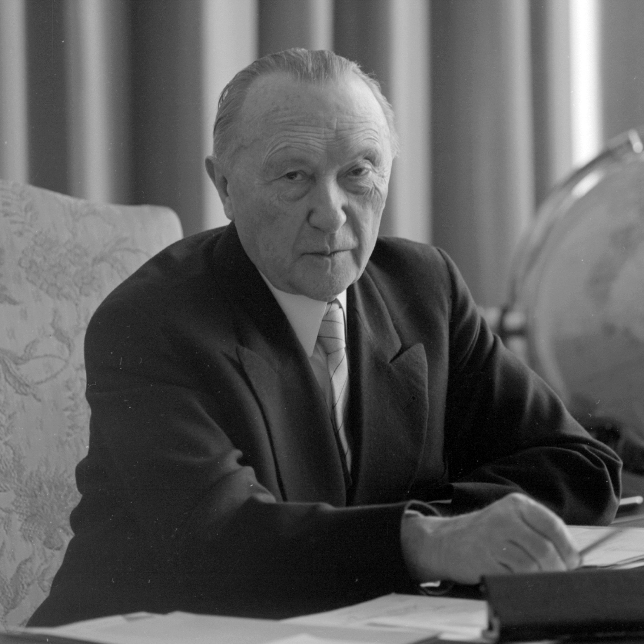 Schwarz-Weiss-Aufnahme von Konrad Adenauer am Schreitisch sitzend