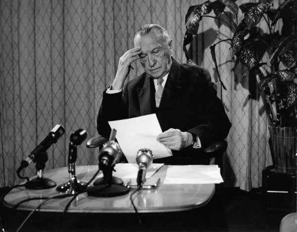Schwarz-Weiss-Aufnahme von Konrad Adenauer an einem Tisch mit Mikrofonen