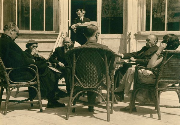 Schwarz-Weiss-Aufnahme von Konrad Adenauer mit anderen Personen in Stühlen auf der Hotelterrasse