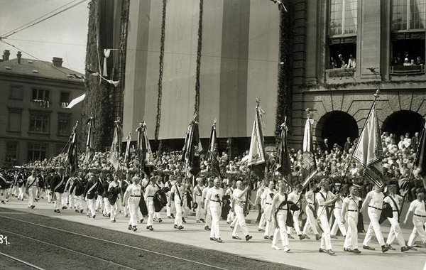 Schwarz-Weiss-Aufnahme von Sportlern mit Flaggen auf einem Umzug