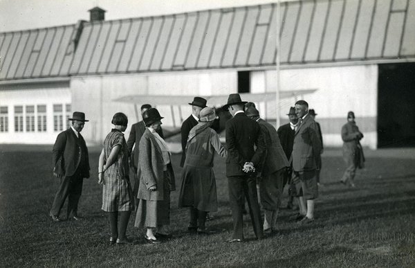 Schwarz-Weiss-Aufnahme von Konrad Adenauer mit seiner Familie und Pressevertretern auf dem Flugfeld