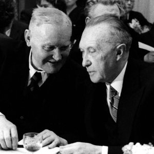 Hans Böckler und Konrad Adenauer sitzen nebeneinander und sprechen mit einander