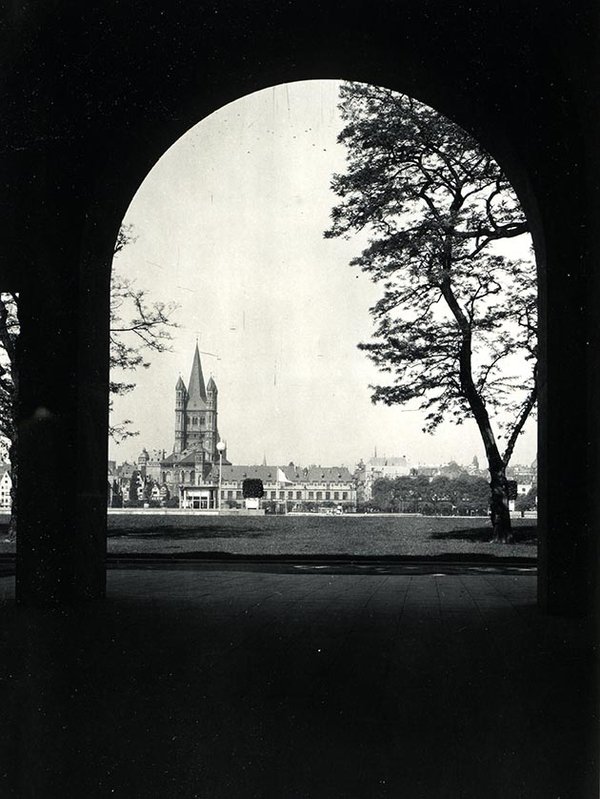 Schwarz-Weiss-Aufnahme von einer Kirche, die durch einen Torbogen fotografiert wurde