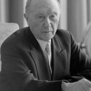 Adenauer sitzt an einem Schreibtisch und im Hintergrund ist ein Globus