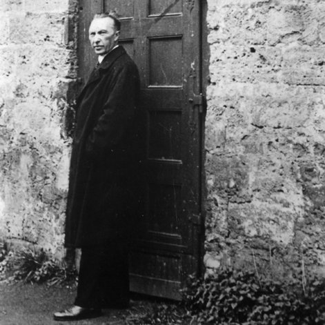 Schwarz-Weiss-Aufnahme von Konrad Adenauer vor einer Holztür