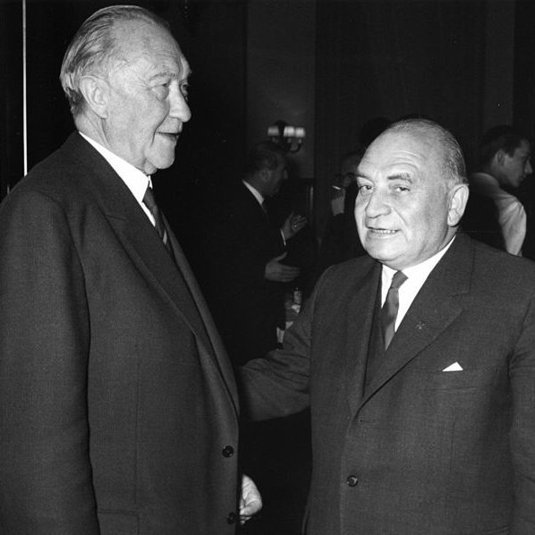 Konrad Adenauer und Wilhelm Johnen stehen zueinander gewandt da.
