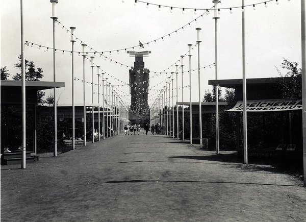 Schwarz-Weiss-Aufnahme von einem mit Lichterketten geschmückten Weg, der zu einem hohen Turm führt