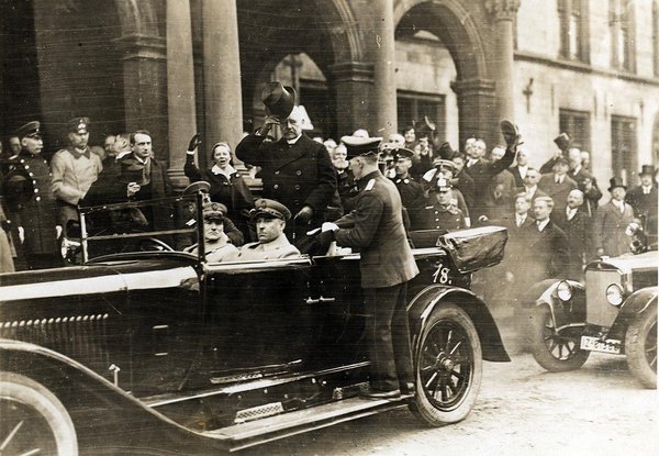 Schwarz-Weiss-Aufnahme von Paul von Hindenburg und Konrad Adenauer in einem Automobil, umgeben von Zuschauern