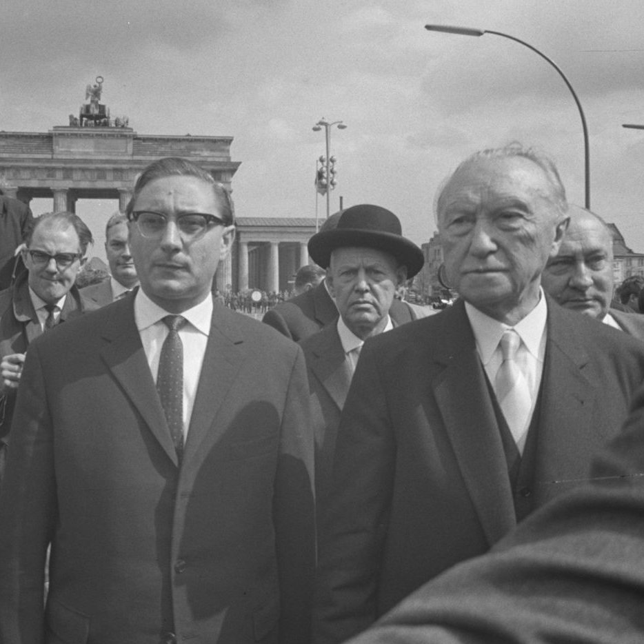 Adenauer und Amrehn stehen in einer Menschenmasse vor dem Brandenburger Tor.
